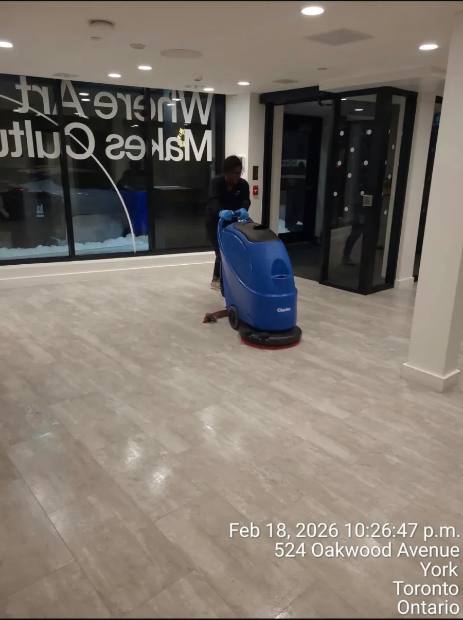 AAFM technician scrubbing a commercial lobby floor with an auto scrubber